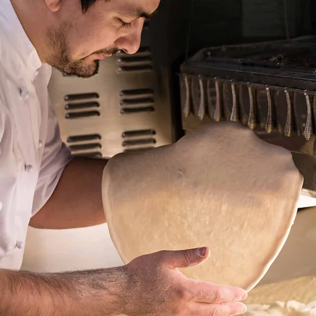 Kokk som baker pizzadeig.