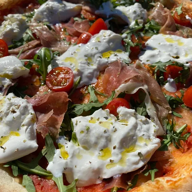 Nærbilde av pizza med spekeskinke og ruccola.